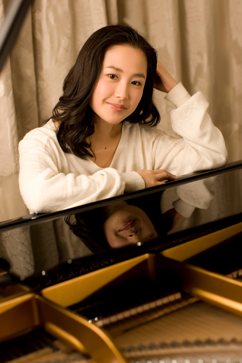 Colour photo of artist in a white shirt sitting at the piano