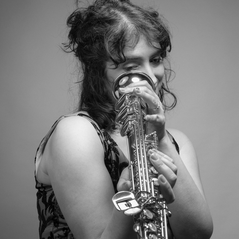 Black and white photo of Betty Accorsi looking through a soprano saxophone