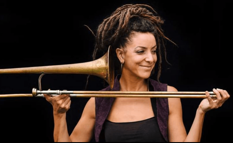 Colour photo of Laura Impallomeni holding her trombone and smiling - taken by Mark Lord