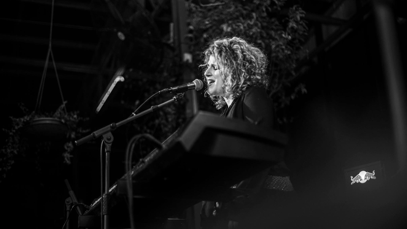 Black and white photo of Lara Eidi singing at a microphone - taken by Myriam B